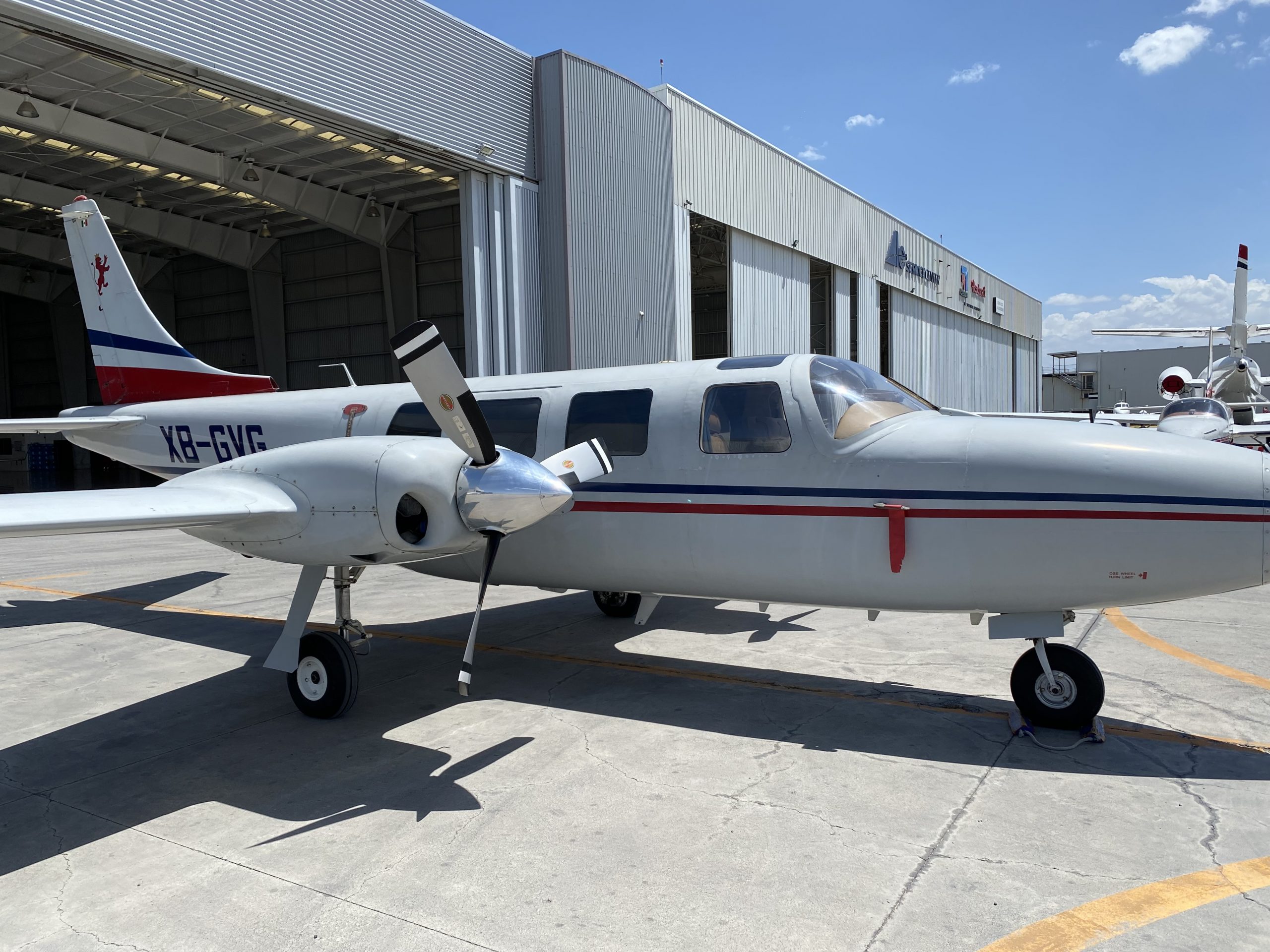 Side view of the XB-GVG aircraft with a white and red paint scheme parked in front of a hangar.
